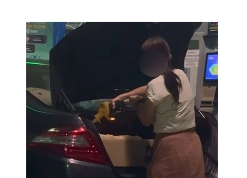 车主将汽油灌入后车厢空桶。