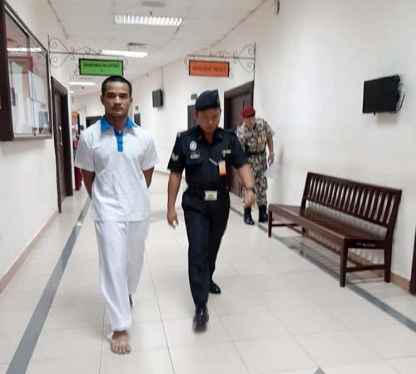 抢劫两家连锁店被判坐牢20年的被告被押离法庭时摄。