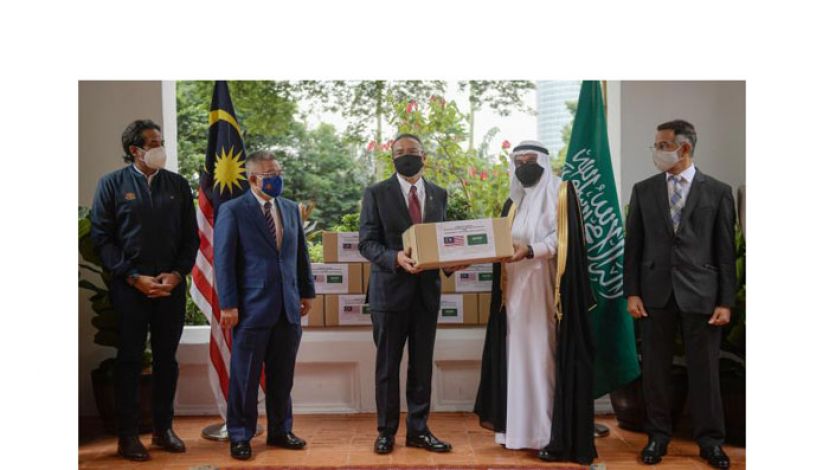 拿督斯里希山慕丁（中）从沙地驻马大使拿督马默胡先（右二）手中接领物资。左起为全国冠病免疫计划协调部长凯里和卫生部长阿汉巴巴。