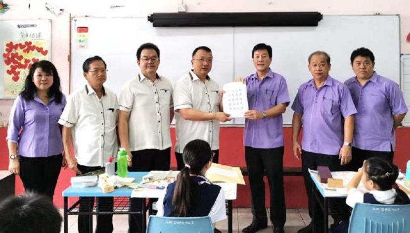 晋汉连省华小董联会会长蔡文铎律师（左四）主持书法比赛揭封仪式后将题目移交给联合筹委会主席王芍强校长，（左三）为联合筹委会主席田松茂。