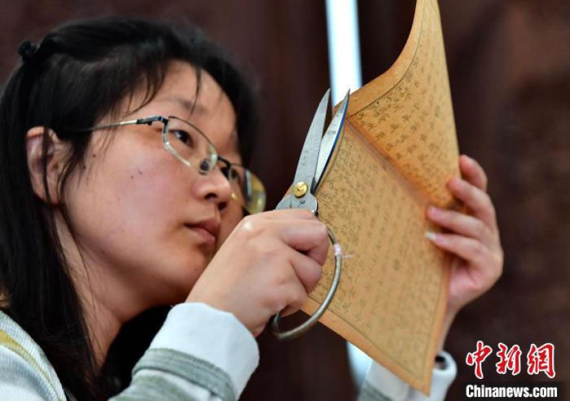 “90后”古籍修复师吴钰正在剪齐修复后的书叶补茬。