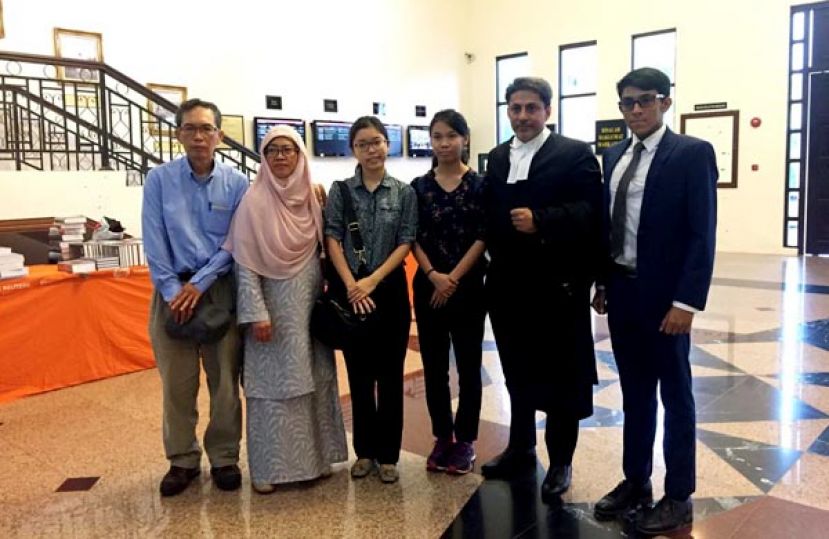 获得家人谅解而撤销控状，一家四口在法庭外拍全家福。 