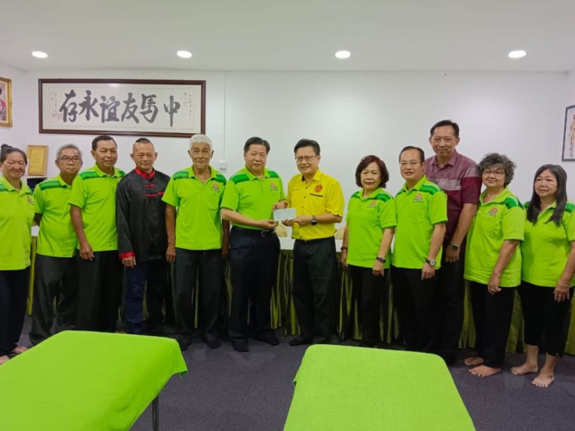 武吉阿瑟区邦议员钱进一(右六)移交拨款予中砂六桂堂宗亲会主席江宗兴（右七）；右起为该会理事翁新惠、龚巧芳、龚世顺、翁新达县议员、甲必丹江丽訇；左起是谢义兰、江昌桦、江先发、方孝丰、江国逸。