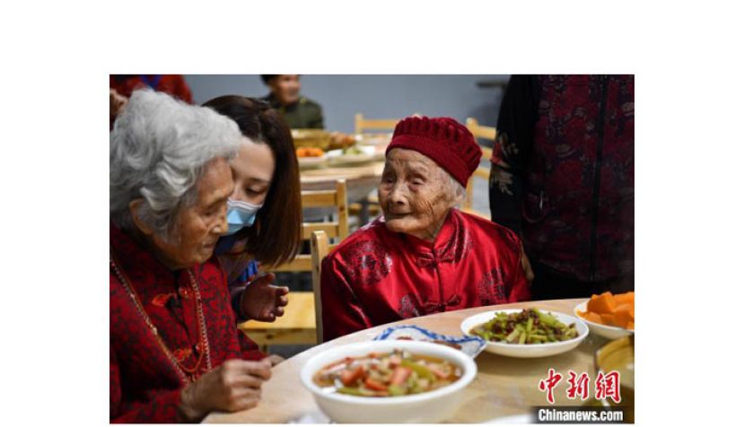121岁的朱郑氏与百岁老人喻泽琴话家常。