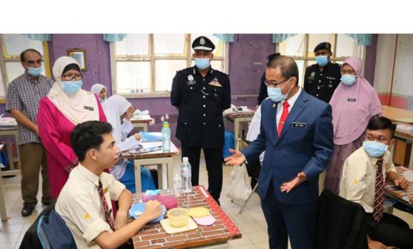 诺阿兹米（前排中）了解学校复课，学生在课室内用餐情况。
