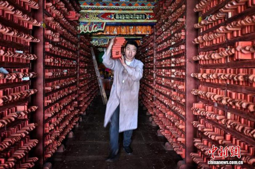 德格印经院藏版库内一名师傅正在搬运印版。