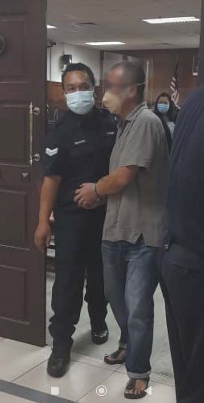 涉嫌奸污亲生女儿的警员遭同僚押离法庭时摄。