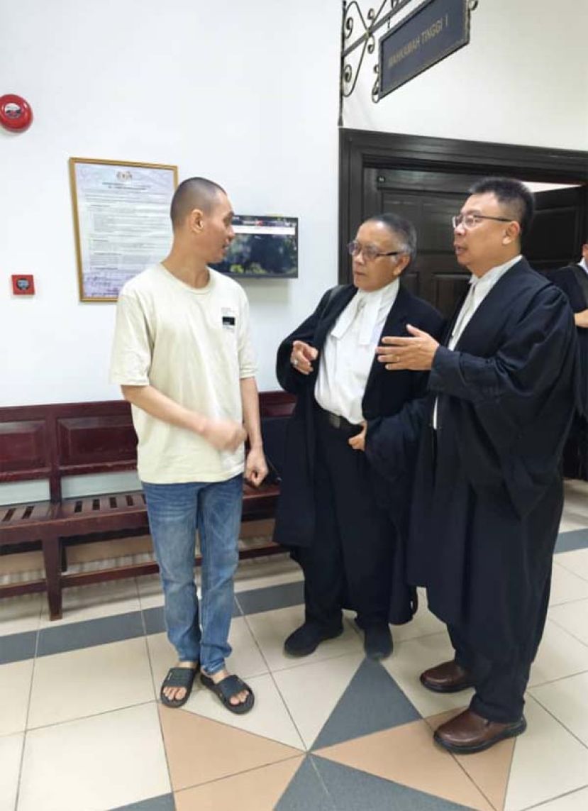 因重量而脱过法律制裁的男子（左）和辩护律师陈文达（右一）以及奥斯曼依布拉欣交谈时影。