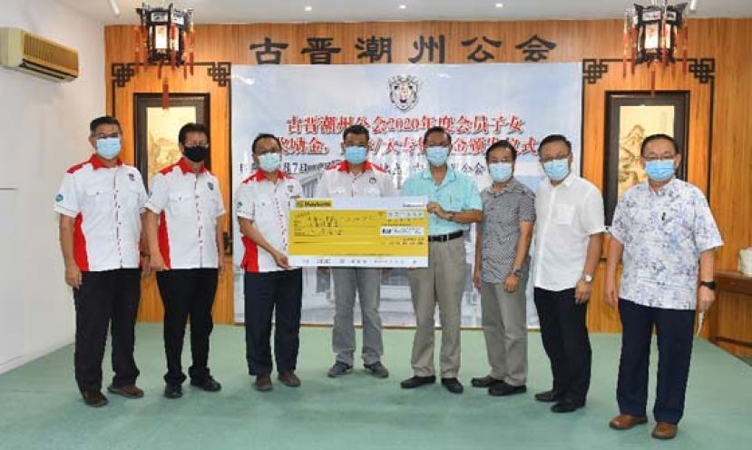 在古晋潮州公会会长周文盛（左四）带领众执委见证下，由第一副会长陈家福（左三）移交3万令吉模拟支票，由古晋中华小学校董会的2  名校董即二小副主席张光福（右四）和二小视察周天龙（右三）领取，右一为古晋潮州公会财政林瑞钊、教育股主任陈崇顺（左二）及教育股  副主任林志烈（左一）。