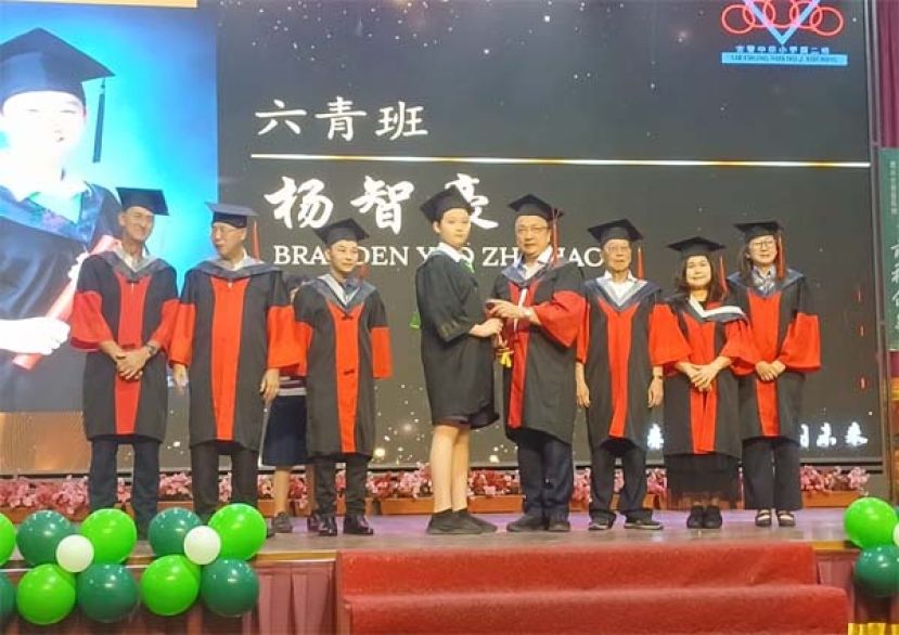 在校董和嘉宾的陪同下，古晋中华小学校董会主席蔡文铎（右四）颁发毕业证书予六青班的杨智豪时影。