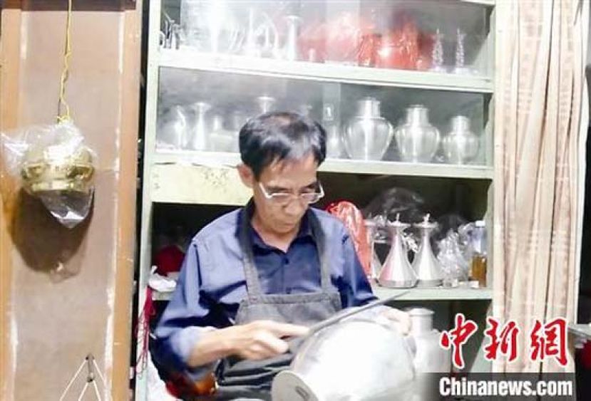 戴清标在打制镴器。