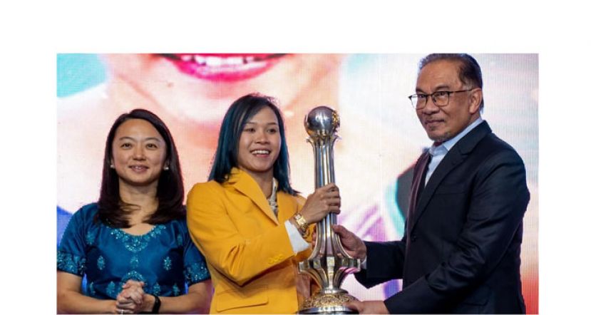 首相安华(右)颁发最佳女运动员大奖予潘德莉拉(中)。左为青体部长杨巧双。