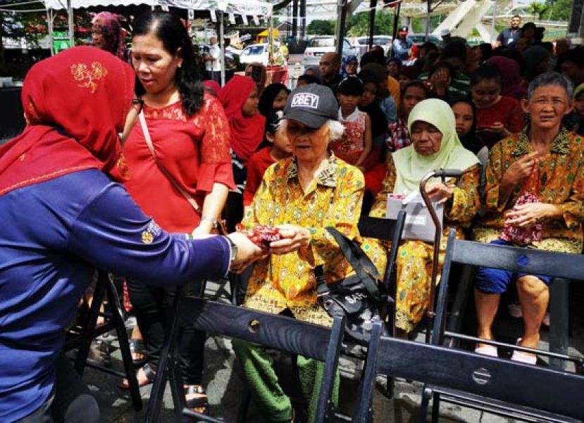 圣诞节筹备会主席莉扎希德妮（左）派发圣诞礼物予老人。