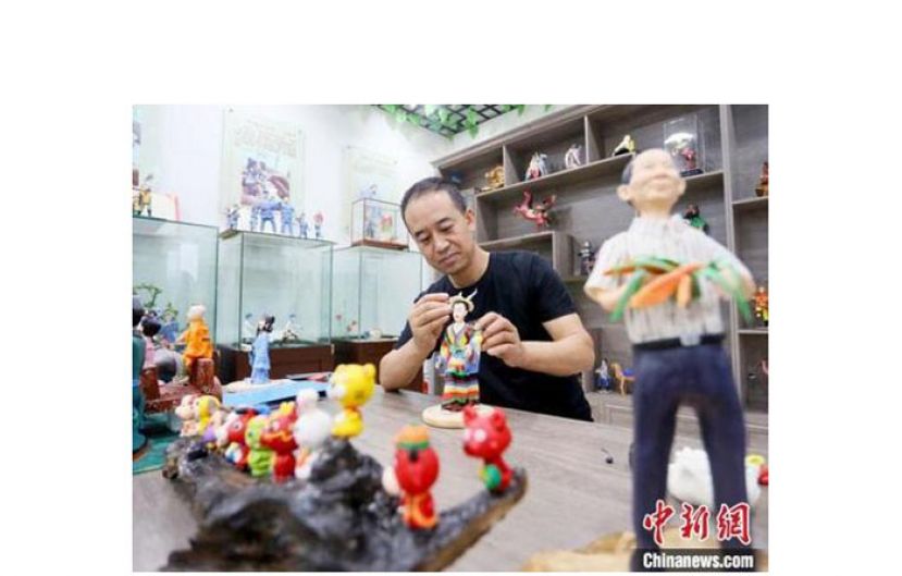 甘肃省非遗项目成州面塑传承人安秋平在用混有高粱、糯米的面泥制作面塑作品。