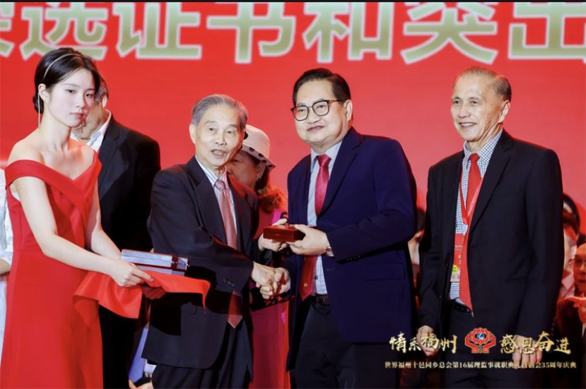 拿督吴标生从中国侨联原主席兼全国政协常委材兆枢 手中接过卓越功勋奖金牌，右一为拿督余志豪。