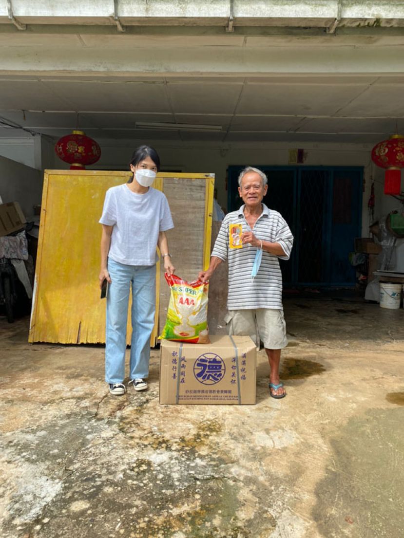 青草路社区A区发展与治安委员会的代表杨明月（左）将紫辉阁的新春布施品移交给青草路区  的有需要家庭。