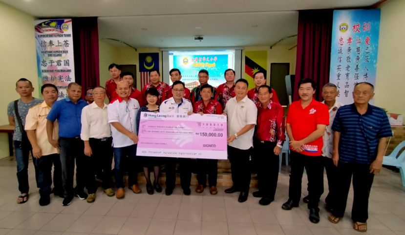 贸消部副部长张健仁（前排中）代表联邦教育部移交15万令吉公益金给22哩大富村华文小学，由校董会主席黄永定（右六）接收。左六为;朋岭区州议员杨薇讳及婆罗洲高原区国会议员威利莫因（右五）