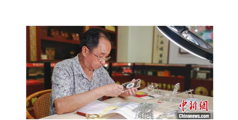 金家栋正在对一枚古代钱币进行鉴定。