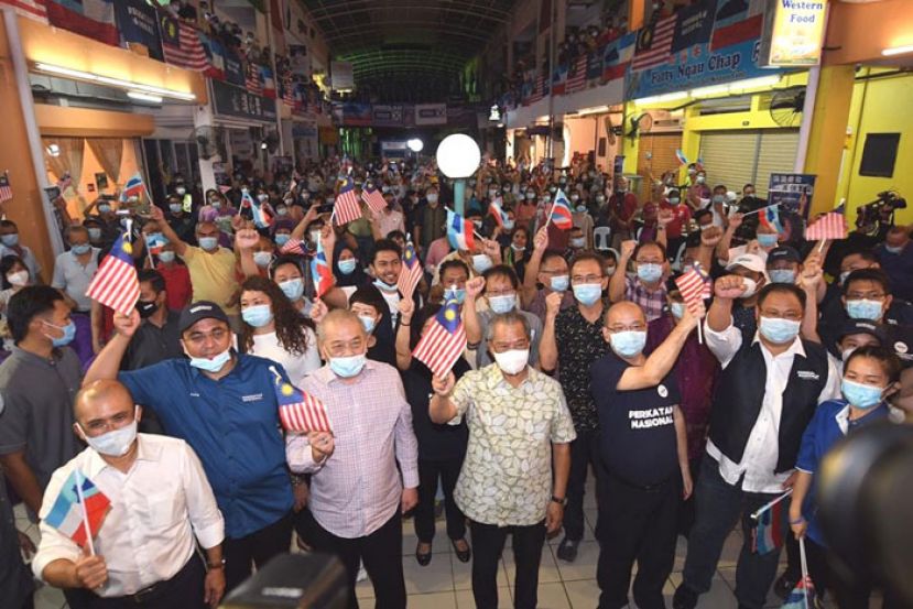 慕尤丁在抵达会场时与民众起挥动辉煌条纹。