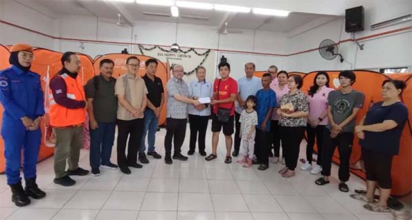 在古晋南市市长拿督黄鸿圣（左7）的见证下，古晋新邦迪卡区民众联谊会主席甲必丹拿督刘思乐（左6）将款项移交予灾黎代表时影。左四为砂人联党峇都林当支部主席薛华东。