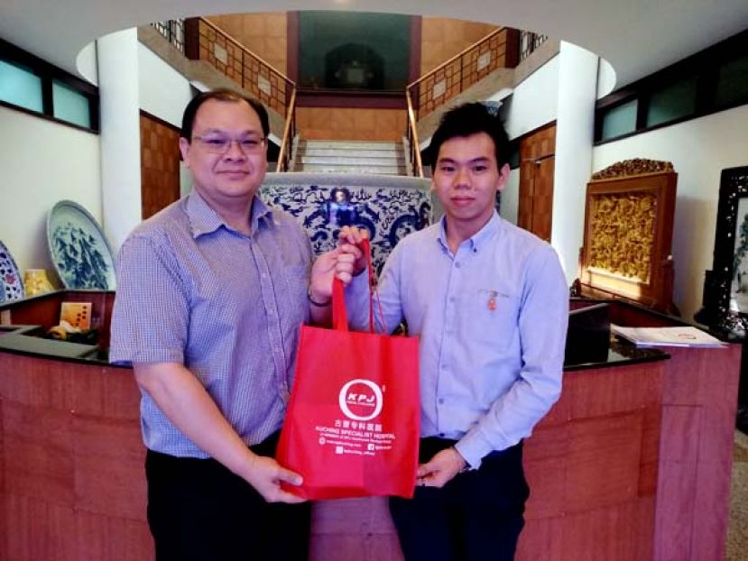 古晋专科医院的市场执行员赖政扬(右)向本报业务发展经理陈朝忠（左）献上贺礼时摄。