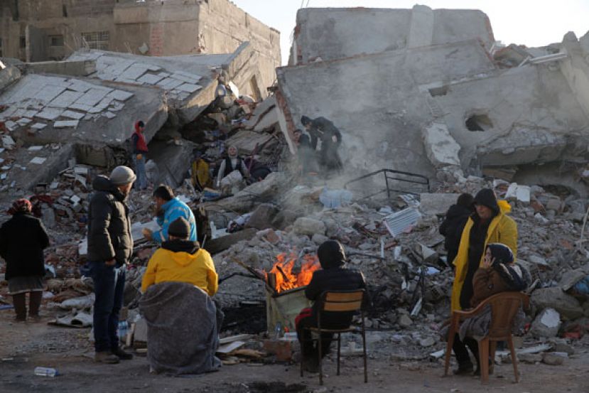 土耳其卡拉曼马拉斯建筑物倒塌，民众坐在一片瓦砾堆前生火取暖。
