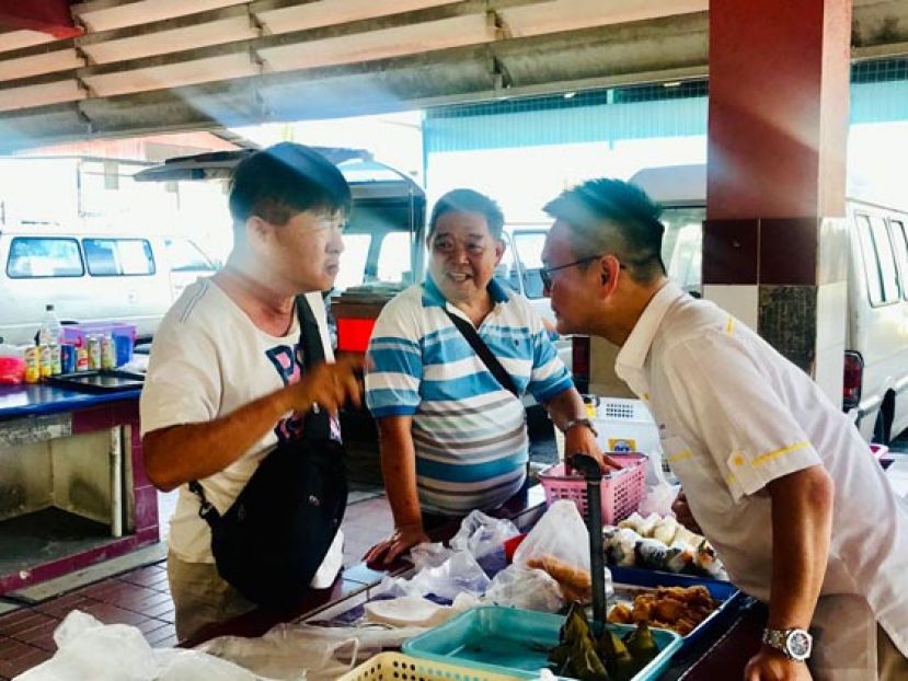  砂人联党青年总团秘书长符祥威（右）到民达华小贩中心和小贩业者交流。