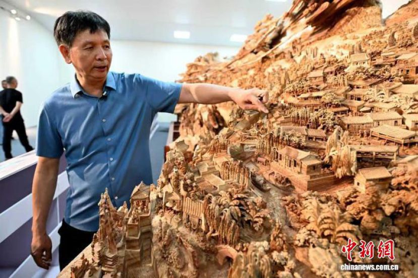 大型木雕《京杭大运河》江南卷首展在福建省莆田市美术馆正式揭幕，图文为郑春辉正在介绍作品的细节。