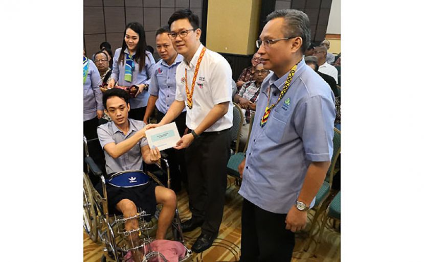 林财耀（右2）移交理赔支票予一名受伤会员。右1为砂社险机构局长菲力桑干。