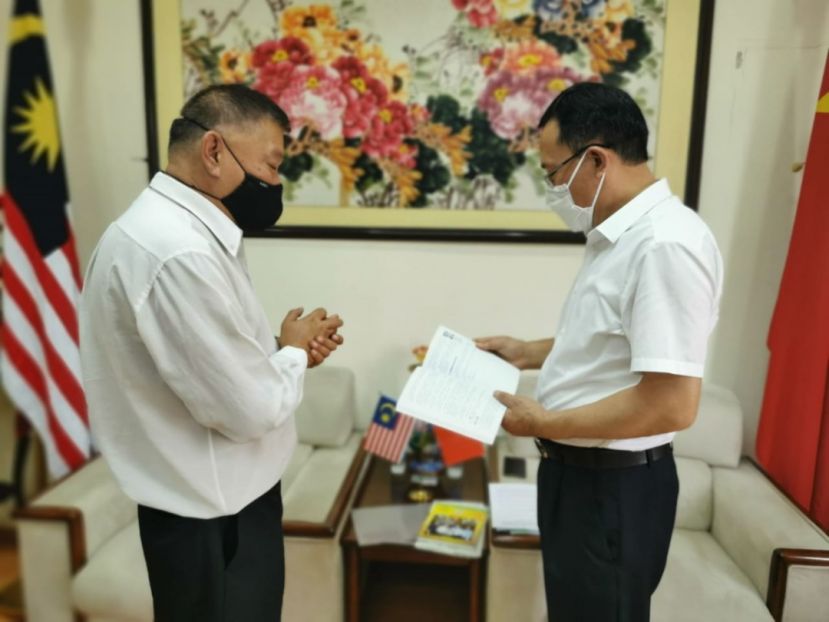 资深前新闻从业员南京大学文学硕士陈中兴（左）向中国驻古晋总领事邢伟平简介其所著《马来西亚砂拉越华文报业发展历程》一书内容。