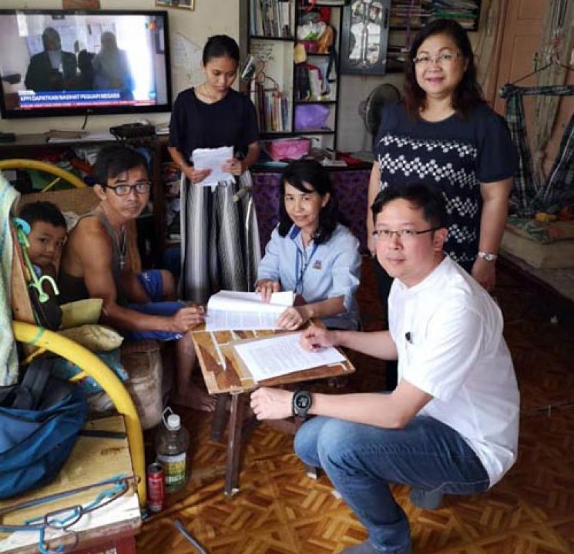  古晋南市市议员及职员到平民房协助行动不便租户更新租约。右一；蹲者为黄廉欢。