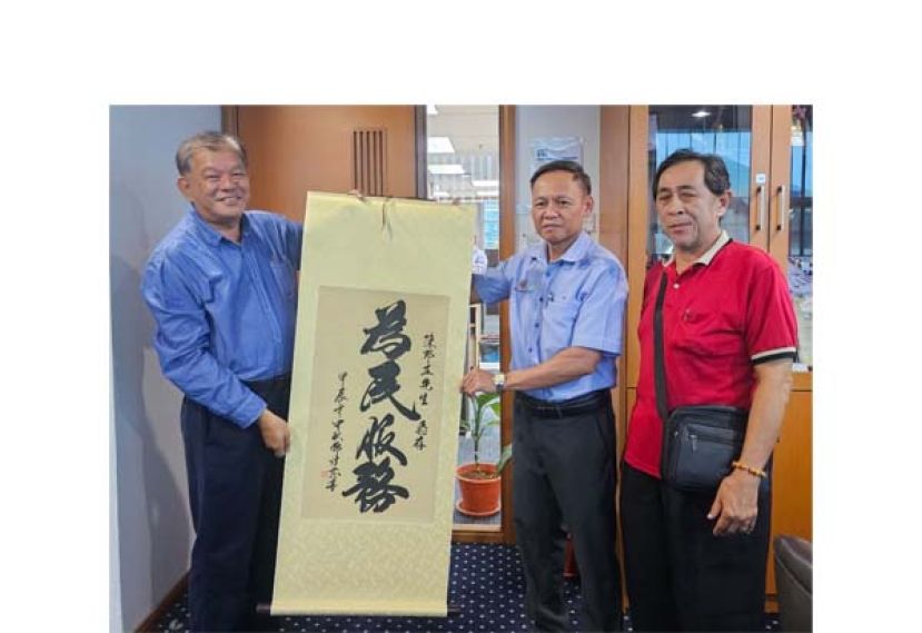 坊间社险福利觉醒推手陈中兴（左）与陈惠生（右）移交&ldquo;为民服务&rdquo; 字幅墨宝予社险砂局长陈邦正（中）。