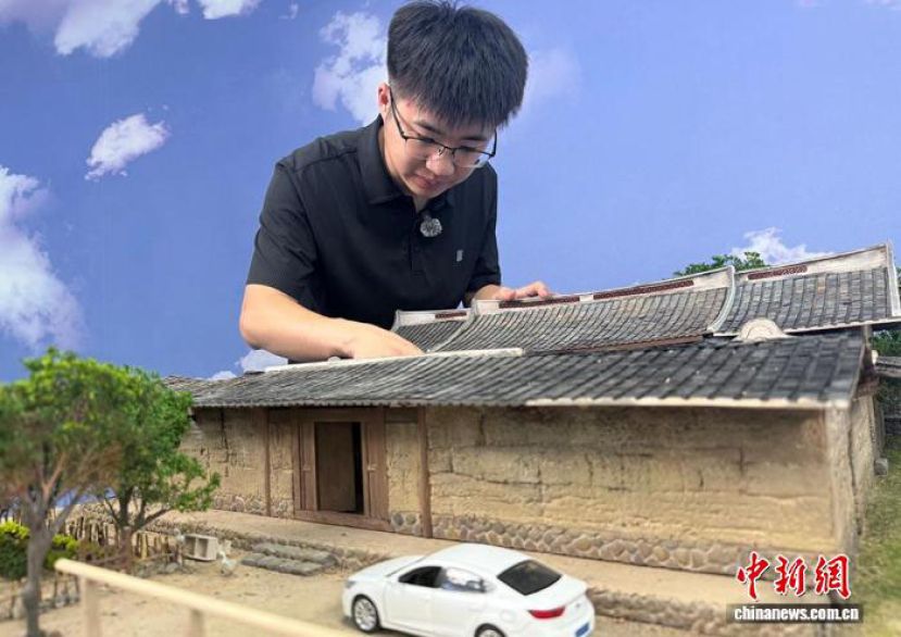 山东烟台龙口市，芦庆欢正在对一座闽南风格的微缩老屋模型进行细节调整。