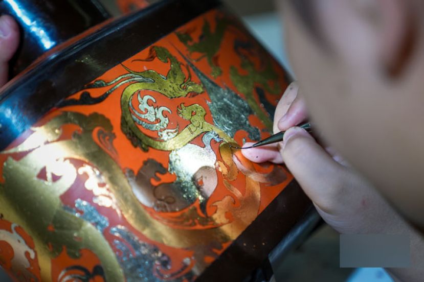 邹传志的徒弟正在给漆器文创产品上色。