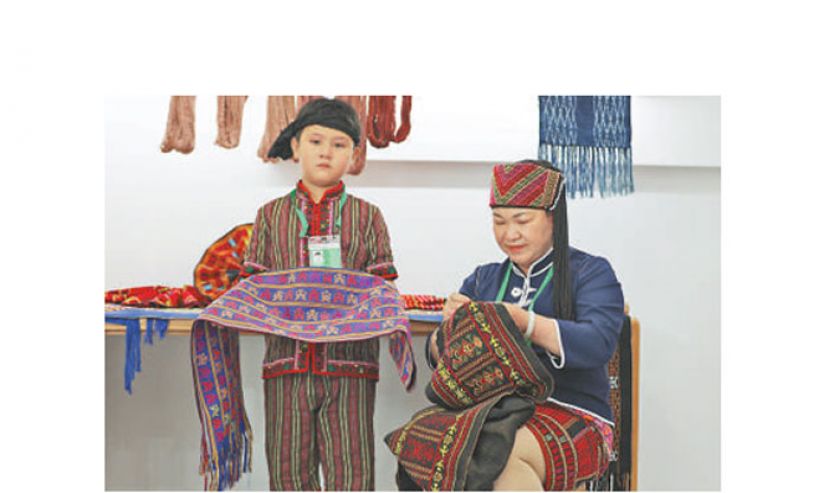 刘香兰和她的孙子在参加黎锦技艺展演。
