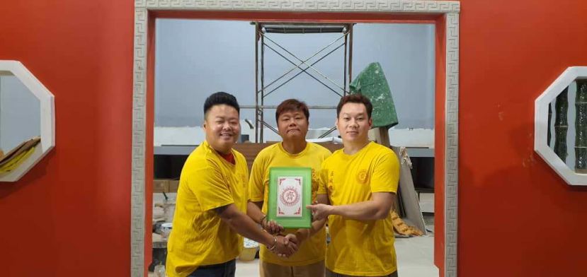 在八点地齐天大圣宫壇主蔡法能(中)见证下，卸任主席江添福代表黄州億(左)移交主席委任状给予第三届(2023至2024年)理事会主席田晓华(右)。