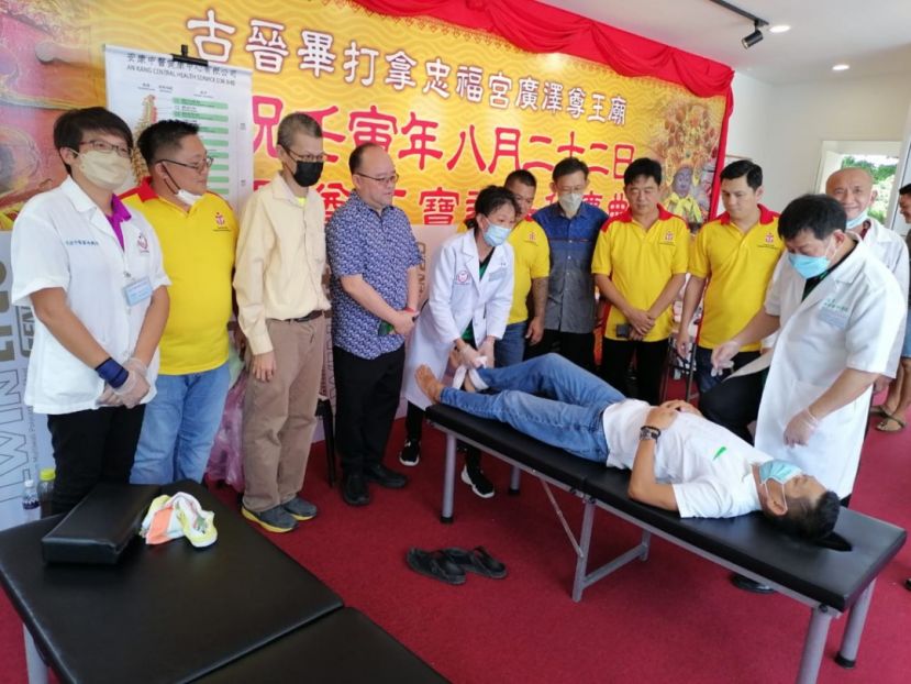 毕打拿忠福宫主席许义华（右3）、顾问薛华东（右4）、筹委主席张荣华（左2起）、李智彊医师、活动顾问甲必丹拿督刘思乐等人看安康中医团队负责人许国模医师（右1）为民众进行义诊。