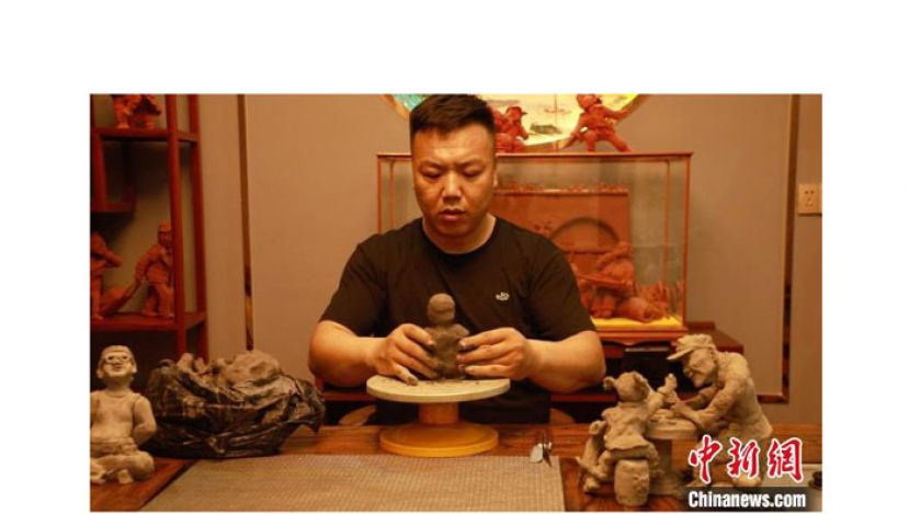 燕华强全神贯注地用泥巴雕刻人像。