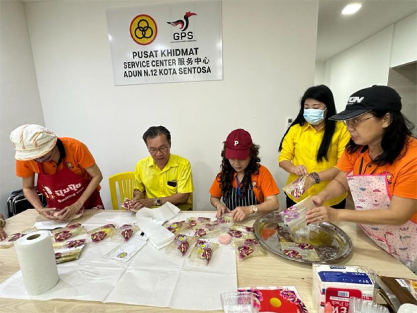 哥打圣淘沙区州议员叶耀星（左二）在古晋福建公会妇女组主任刘碧云（中）及人联党哥打圣淘沙支部妇女组主席锺昉霏（右二）的陪同下，协助包装已完成的部分冰皮月饼。