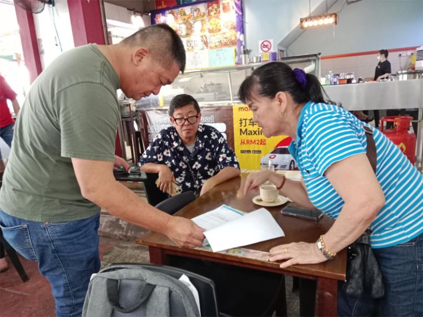 巴都林当区州议员施志豪（左）向民众讲解并协助办理注册申请砂拉越政府推出的"年长者健康福利计划"（SCHB）及"砂拉越基本需求援助计划援助金"（SKAS）详情，同时也处理各项民生事务。