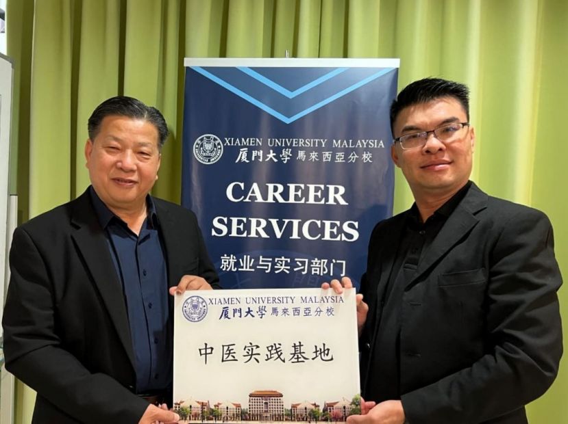 砂医总会长江宗兴（左）由厦门大学（马）分校代表苏智鸿（右）颁中医实践基地扁牌。