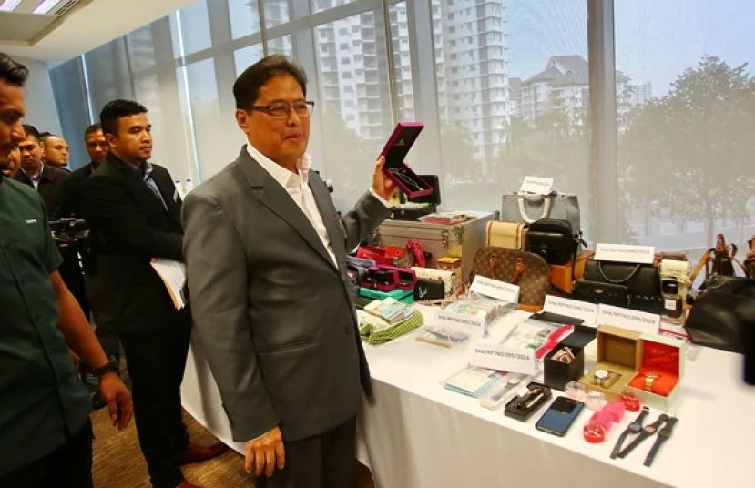 反贪会首席专员丹斯里阿占峇基召开新闻发布会时展示起获的大量现金、金饰、名表、手机、手提电脑等物品。