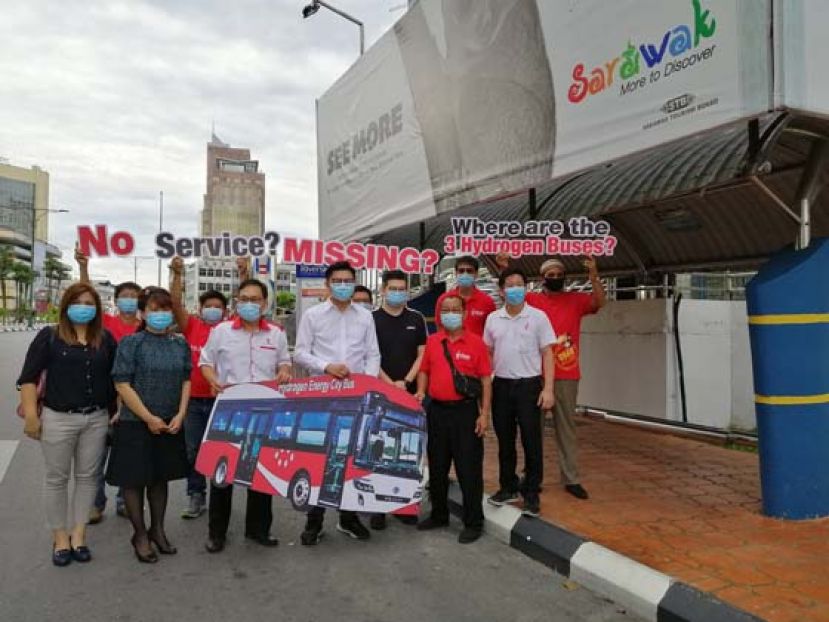 张健仁与该党干部展示氢气巴士的模型板及氢气巴士消失的告示牌。