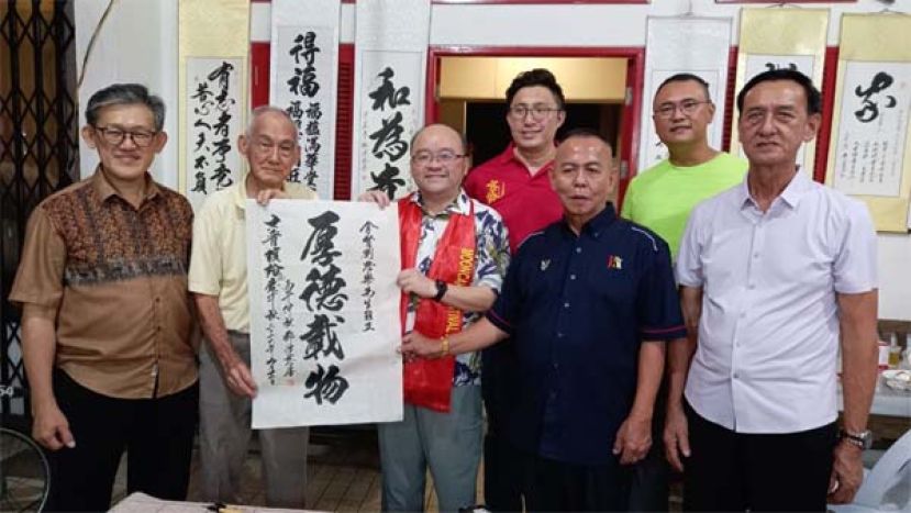 书画家邓访慈（左2）在古晋缤纷文化庆中秋赠&ldquo;厚德载物&rdquo;墨宝予甲必丹拿督刘思乐。右起为甲必丹唐才茗、甲必丹陈俊贤、庆典主席甲必丹林传政、甲必丹蔡明进；左是庆典顾问薛华东。