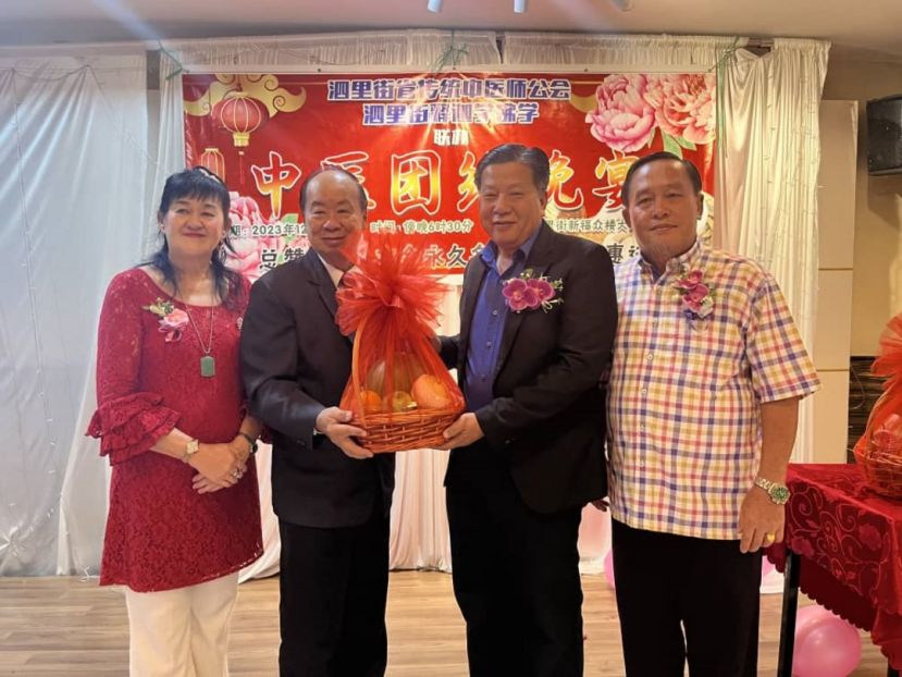 砂医总会长江宗兴（右2）从泗里街省传统中医师公会主席叶绍荣手中接过水果礼蓝；右为泗里街释迦学佛会主席叶惠进；左为俞燕希。