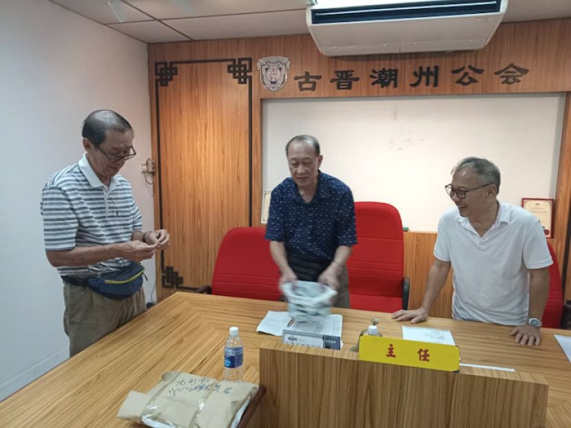 古晋潮州公会选举委员会的顾问沈德锐（左起）、主任杨金木和副主任沈利国在进行执委会选举候选人抽签竞选编号程序时影。