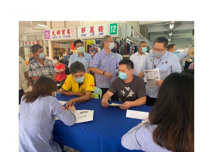 古晋南市市政局市长拿督黄鸿（后右1）前往肯雅兰菜小贩市场巡视“自雇人士社会保险计划”柜台。