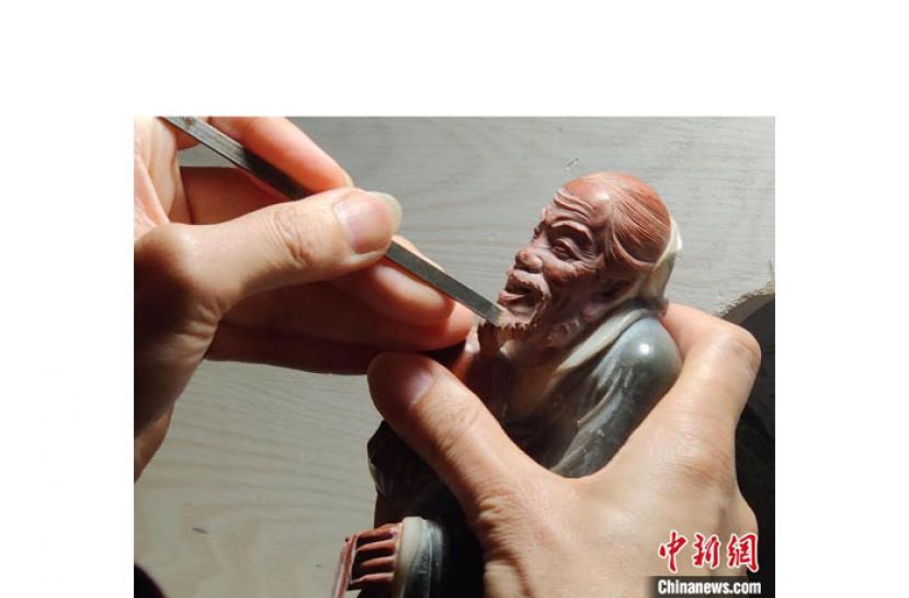 寿山石雕刻大师林国仲正在雕刻作品。