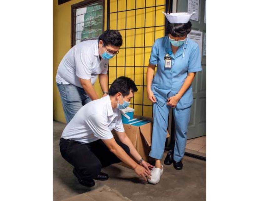 越邦集团志愿团队在古晋中央医院帮助护士试穿医用木屐鞋。