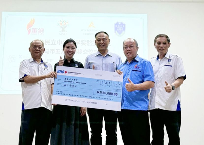 董总代表李利名移交模拟支票给石角民立中学，由民中董事会财政彭志拔代表学校接收，校长赖淑珍和砂董联会副秘书长关伟华见证。右一为民中董事会秘书长温武有。